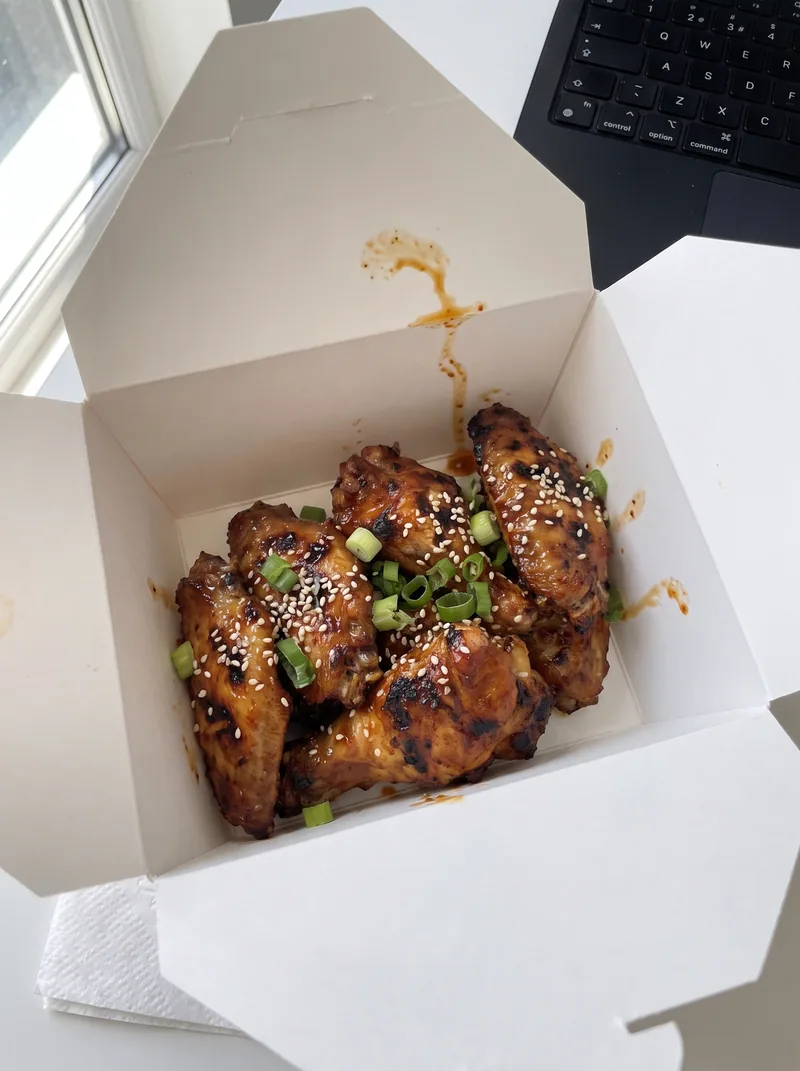 A takeaway box with grilled chicken wings
